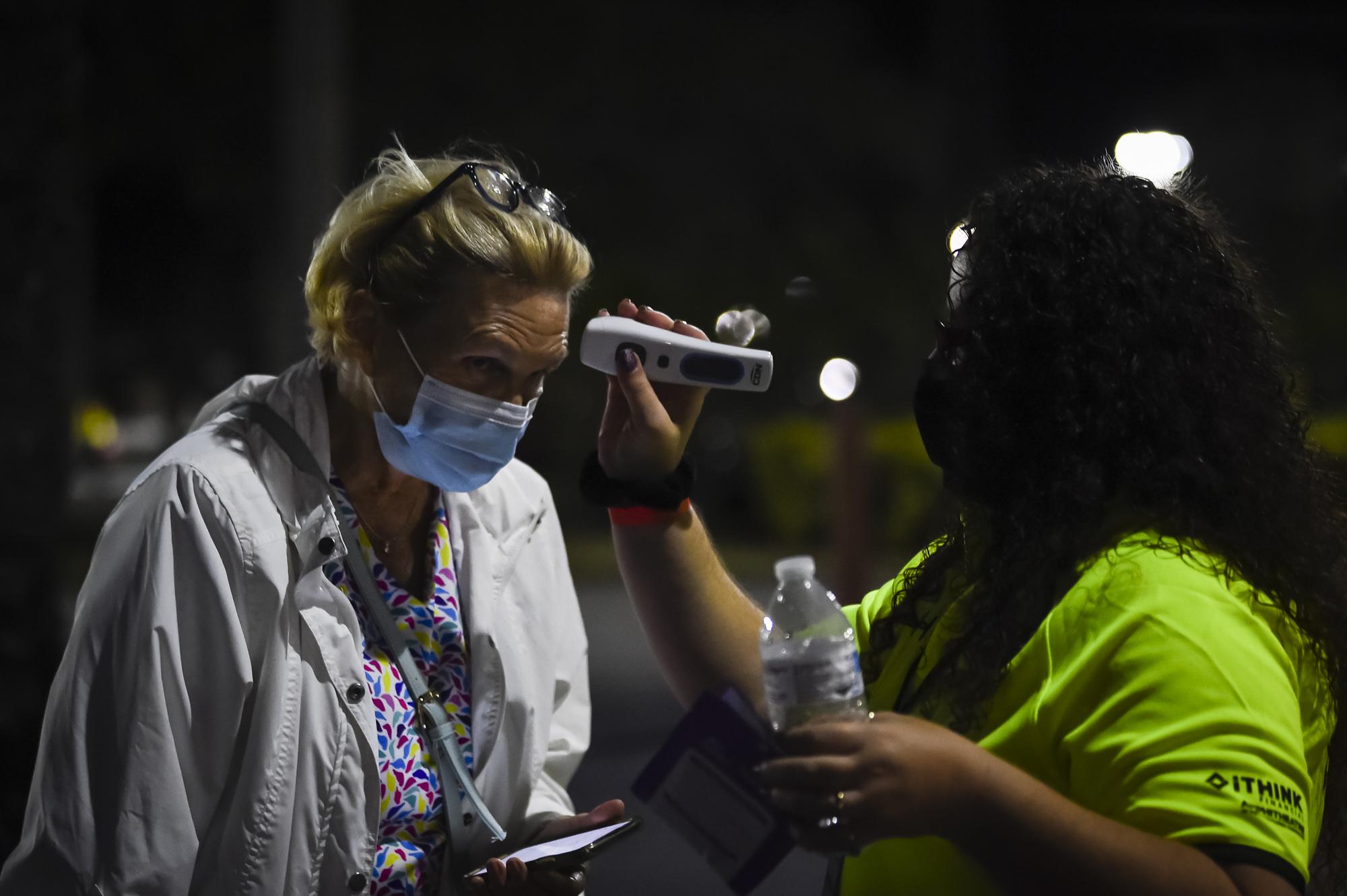 A woman wearing protective face masks has their temperature checked before entering the performance â€œLa BohÃ¨meâ€ during the opening night of the first Palm Beach Operaâ€™s outdoor festival, at the South Florida Fairgroundsâ€™ iTHINK Financial Amphitheatre in West Palm Beach, Florida, U.S., on Friday, Feb. 19, 2021. Photographer: Eva Marie Uzcategui/Bloomberg