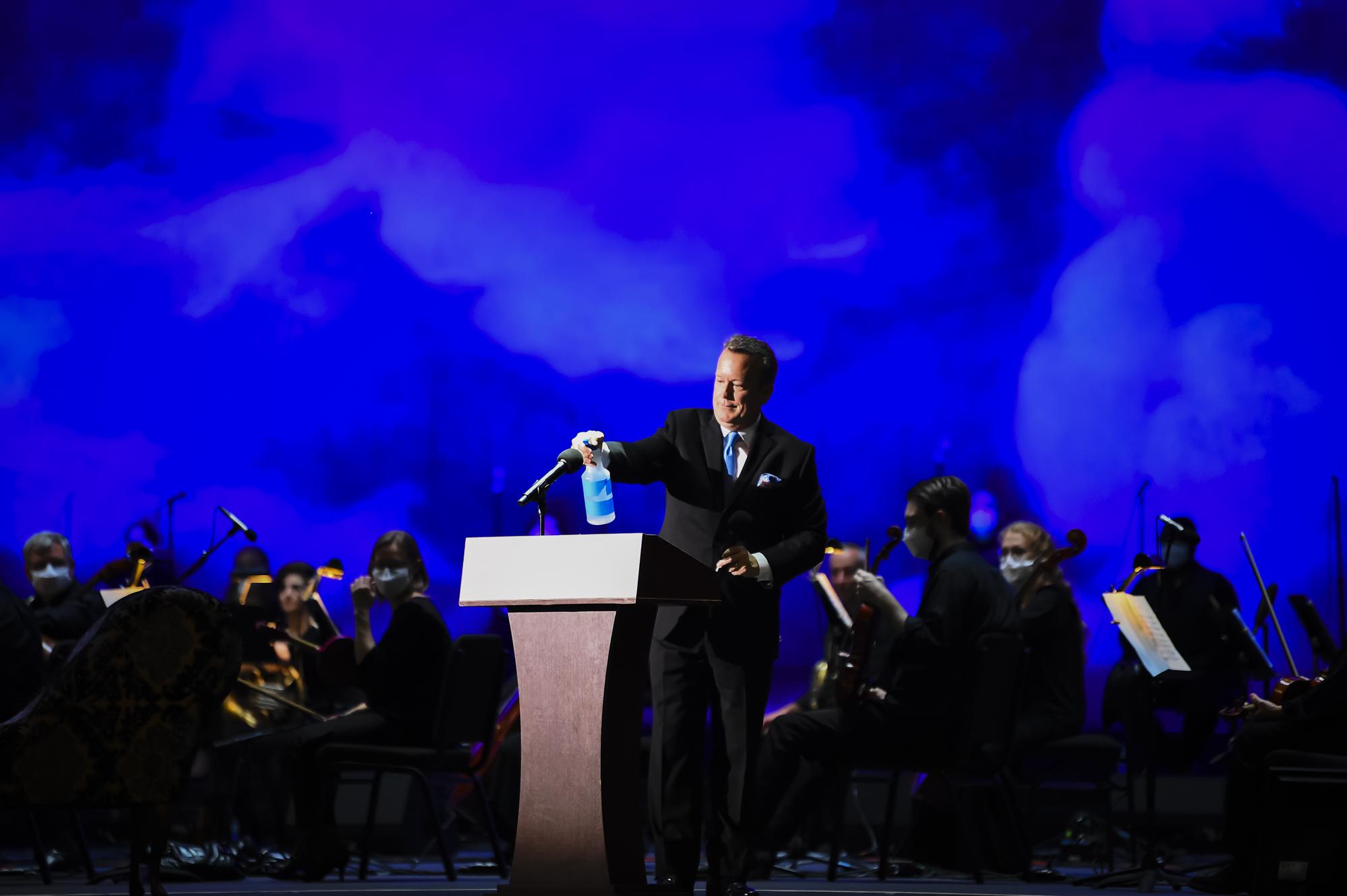 Palm Beach Opera reopens - The host sanitizes the microphone during the opening...
