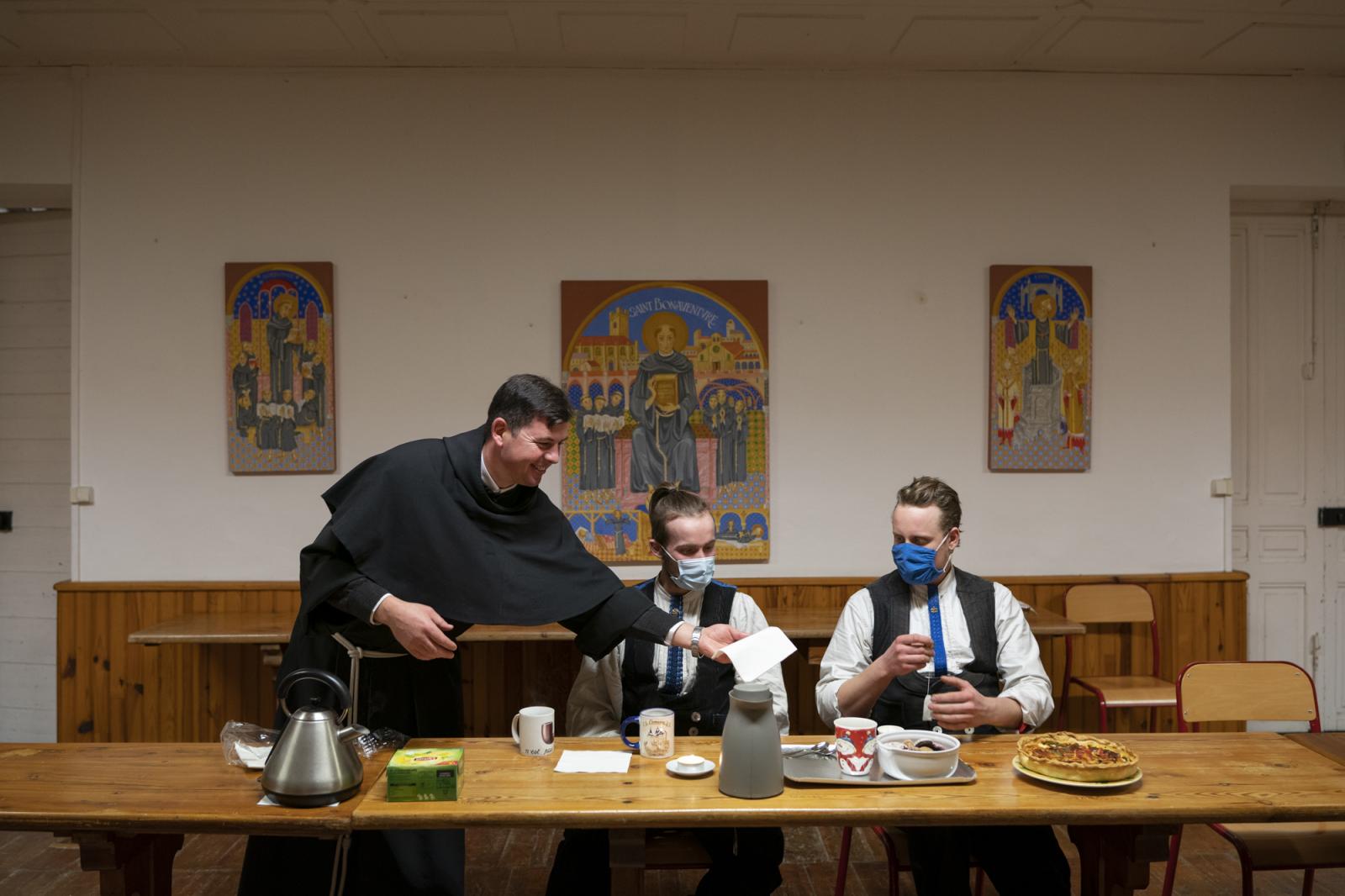  -  Matthias (C) and Ben wearing face masks sit at the table in the common area of the Franciscan...