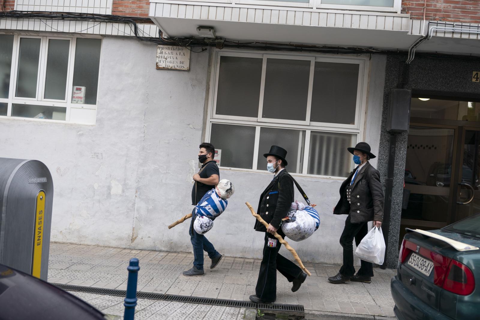   - Ismail (L), Matthias (C) and Ben walk wearing face masks on the street of Santurtzi as they carry...