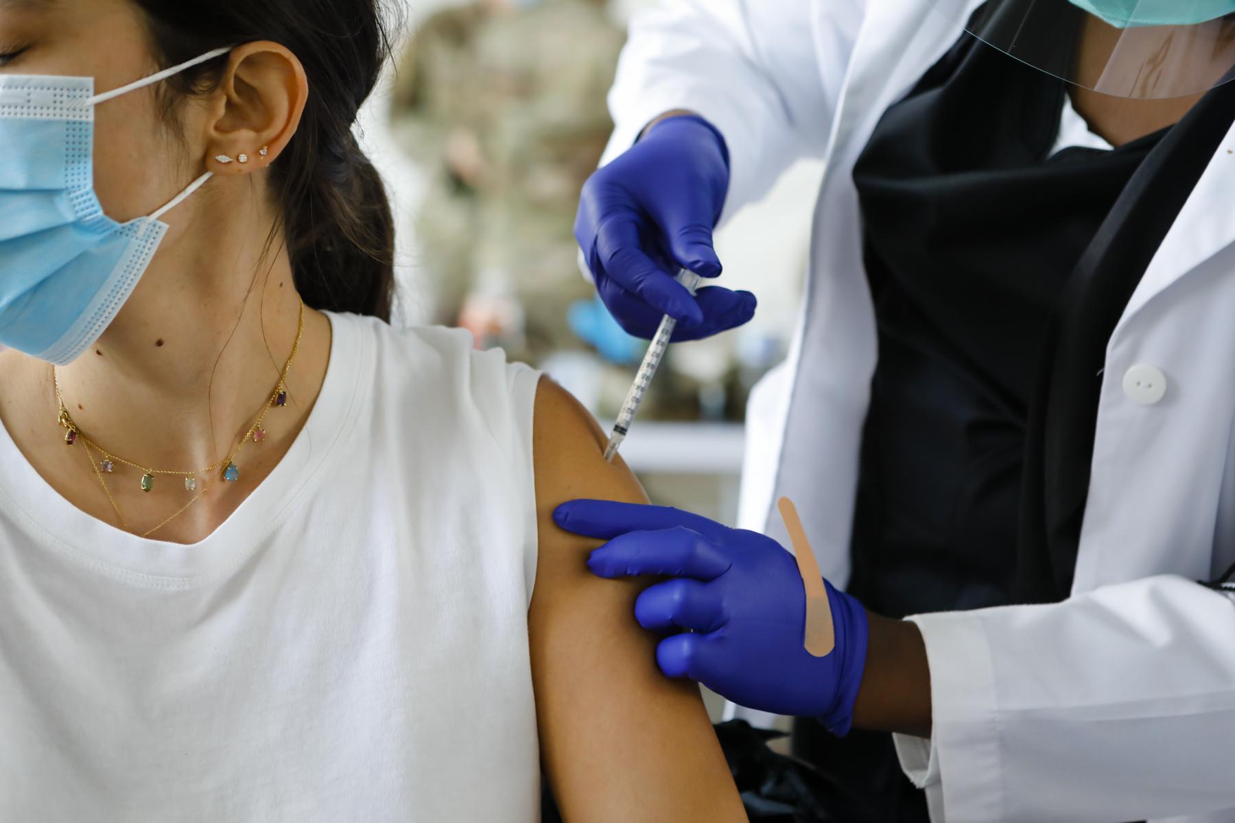 FEMA vaccination facility in North Miami - A health care worker immunizes a woman with the Pfizer -...