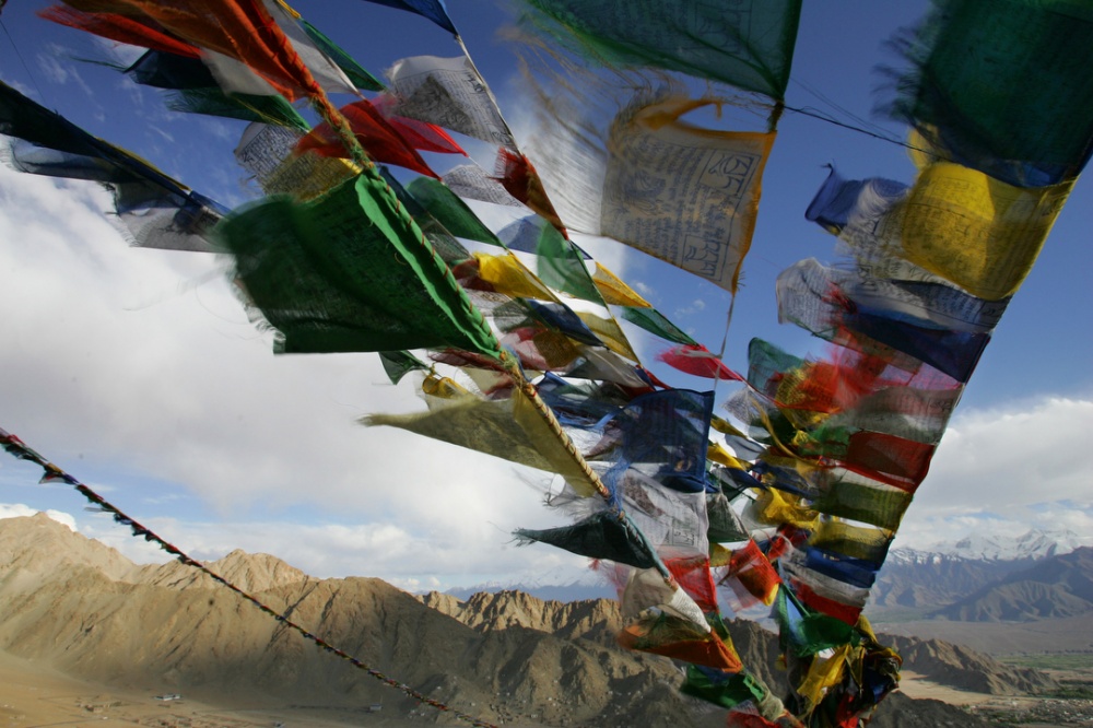 Tibetan prayer flags fly over t...altitude mountainous landscape.