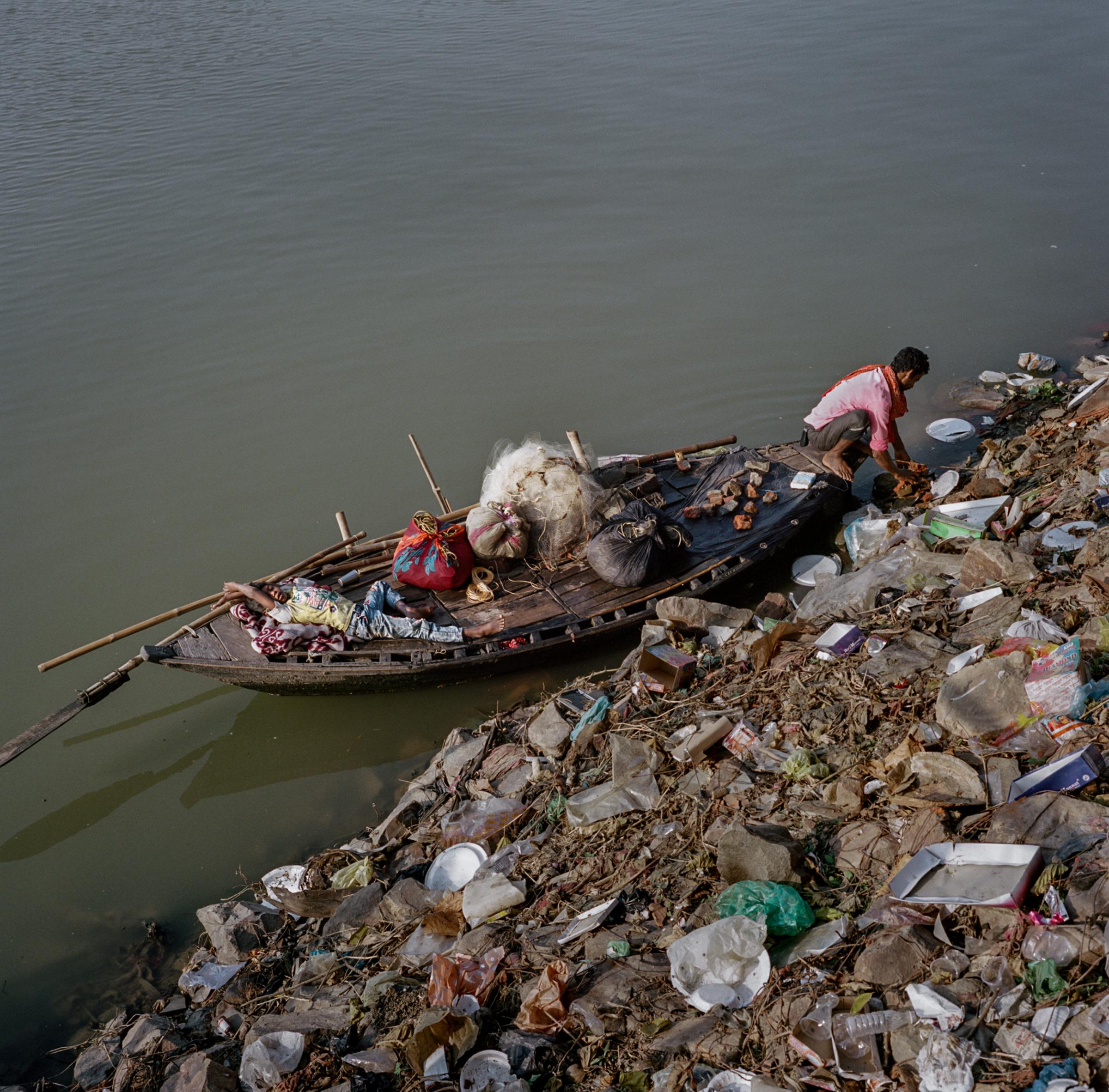 Fisherman Babu Sahni, 30, and his son Himanshu Kumar Sahni, eight, approach a bank on the Punpun River, a Ganges tributary. Throughout rural India, trash collection is rare, and ad hoc dump sites like this one are common. Most plastic waste in the ocean gets there by washing off the land. 