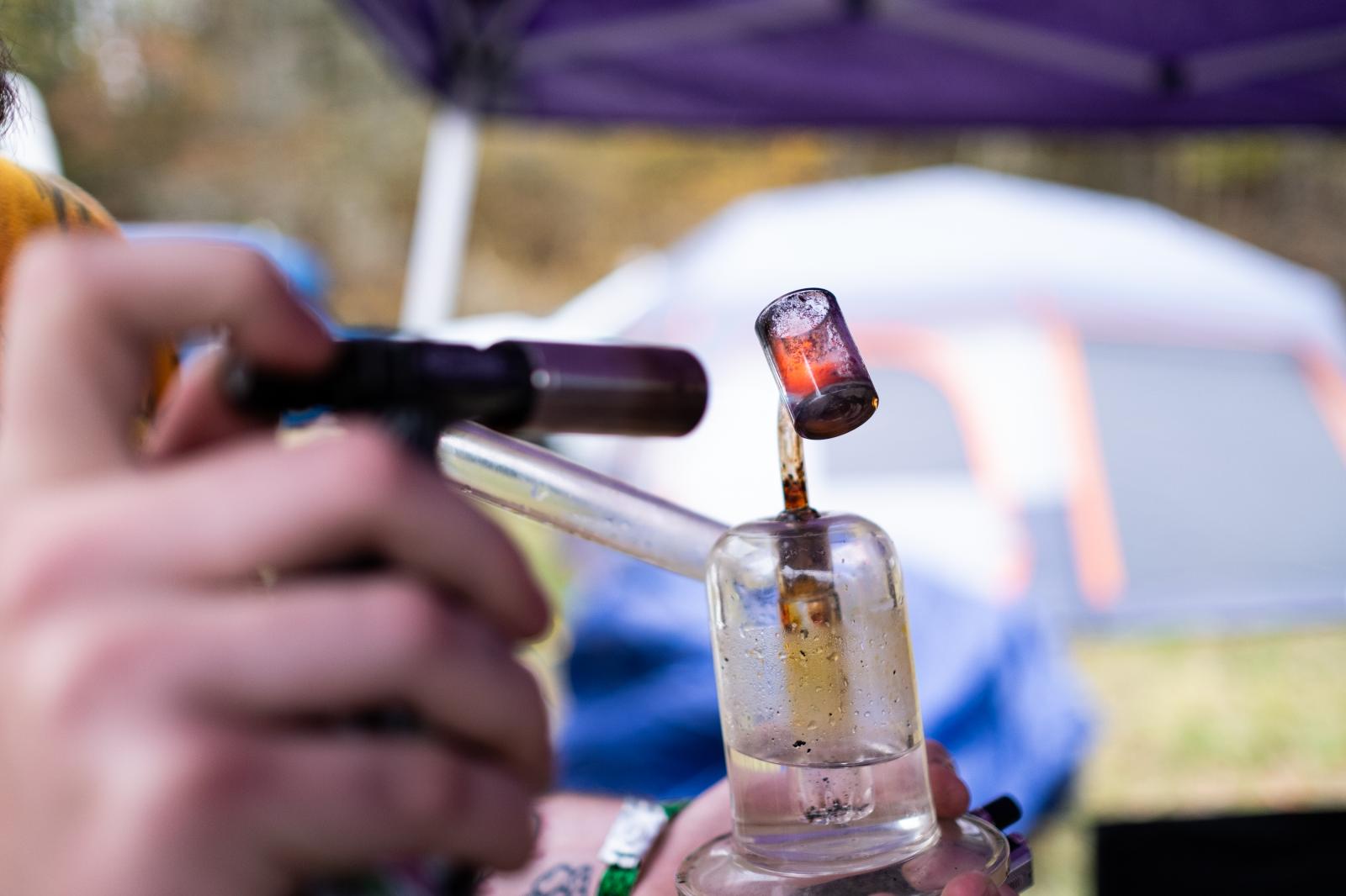 A vendor at the Hemp Festival cleans a dab rig used for vaporizing cannabis concentrates.