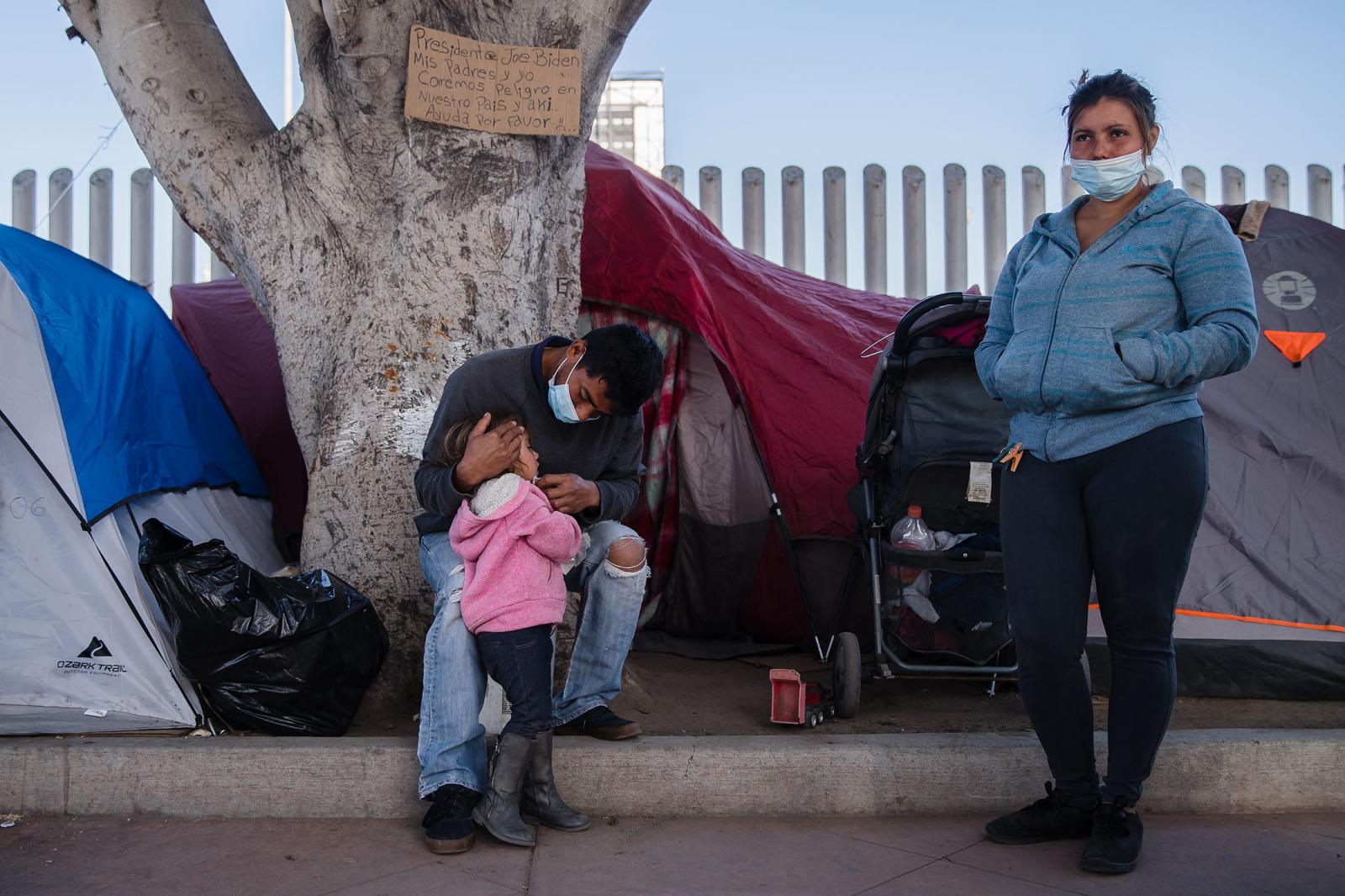 Berta Lidia Caballero (right) who is from Honduras stands near her husband Christian Antonio Reyes Flores and her daughter, Stacy Anai Reyes Caballero in front of El Chaparral port of entry in Tijuana, Mexico on March 2, 2021. They are waiting in hopes of entering the United States along with a few hundred of other migrants and asylum seekers sleeping in front of the port of entry.