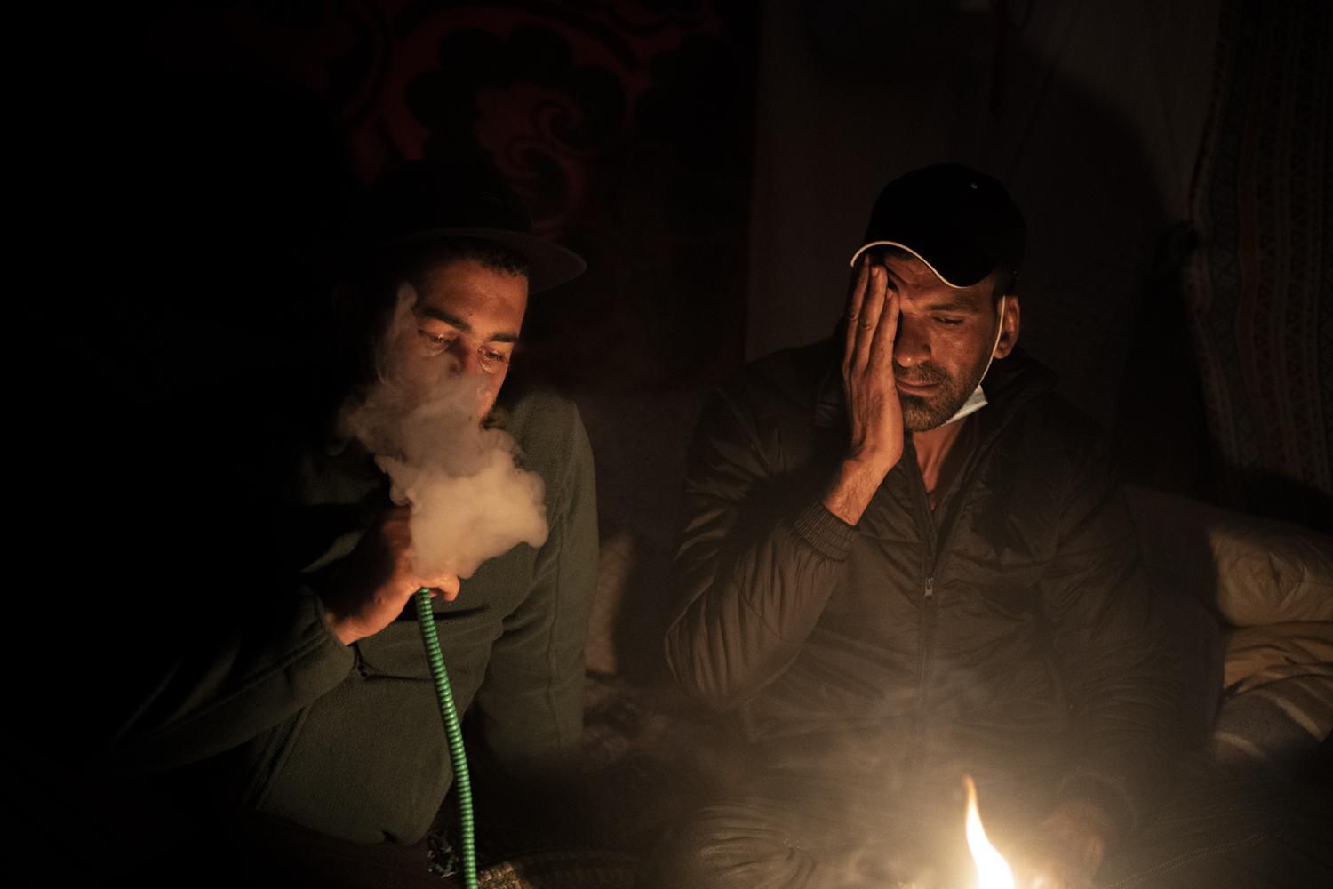 Las Raí­ces Camp - Migrants smoke a hookah, also known as Arjilah or Shisha...