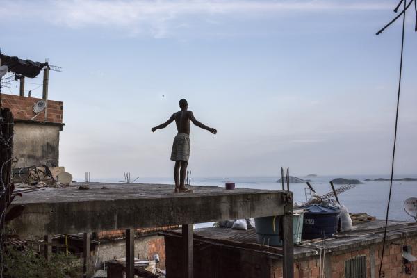 Vidigal - Boy flies a kite from a rooftop in Vidigal overlooking...