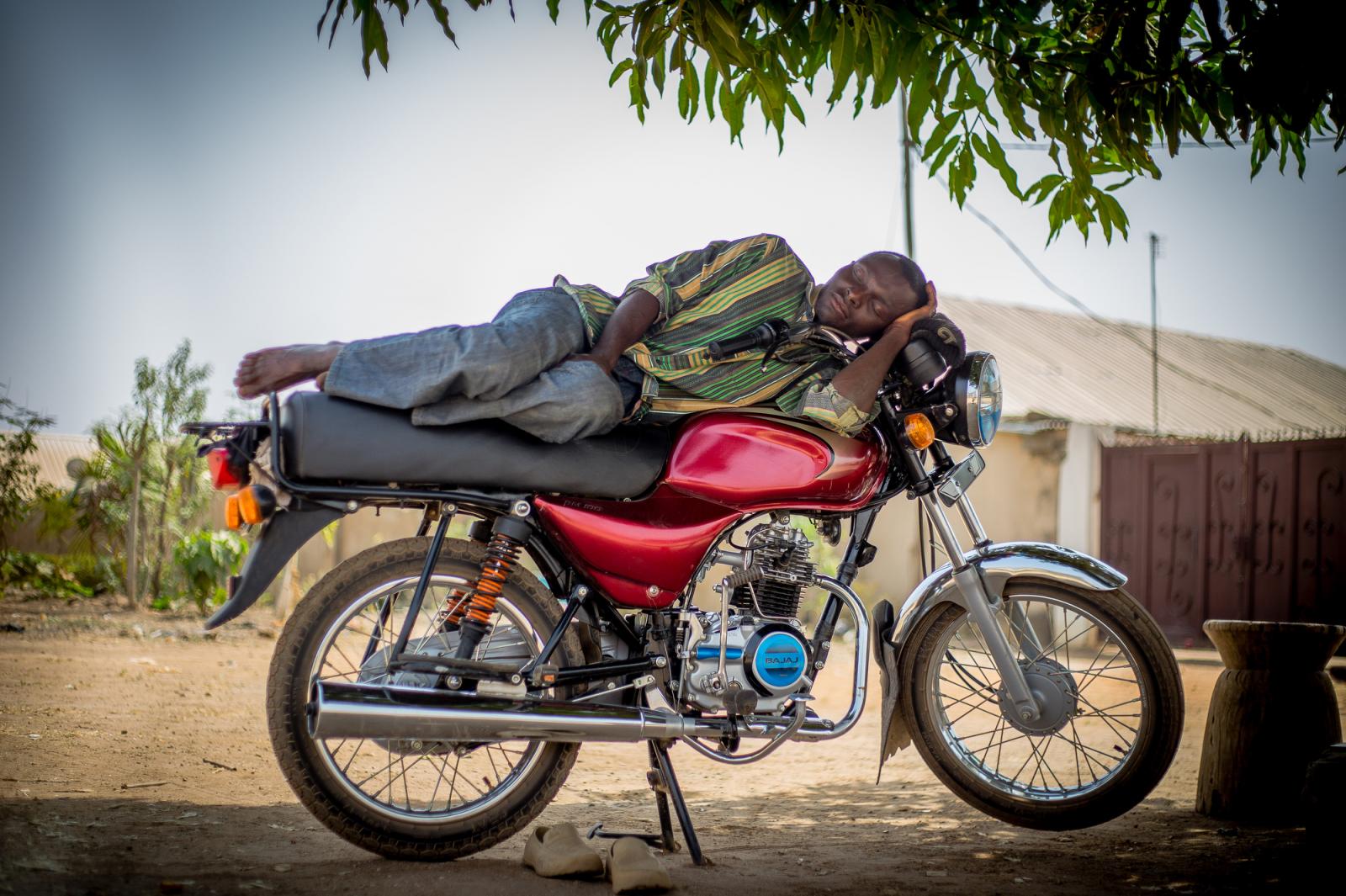 A motorcycle taxi rider takes a...de of a tree in Abuja, Nigeria.