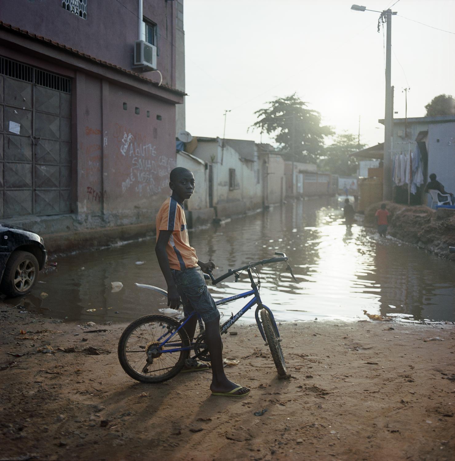 Angola - Flooded street blocks the way for a boy with his bicycle...