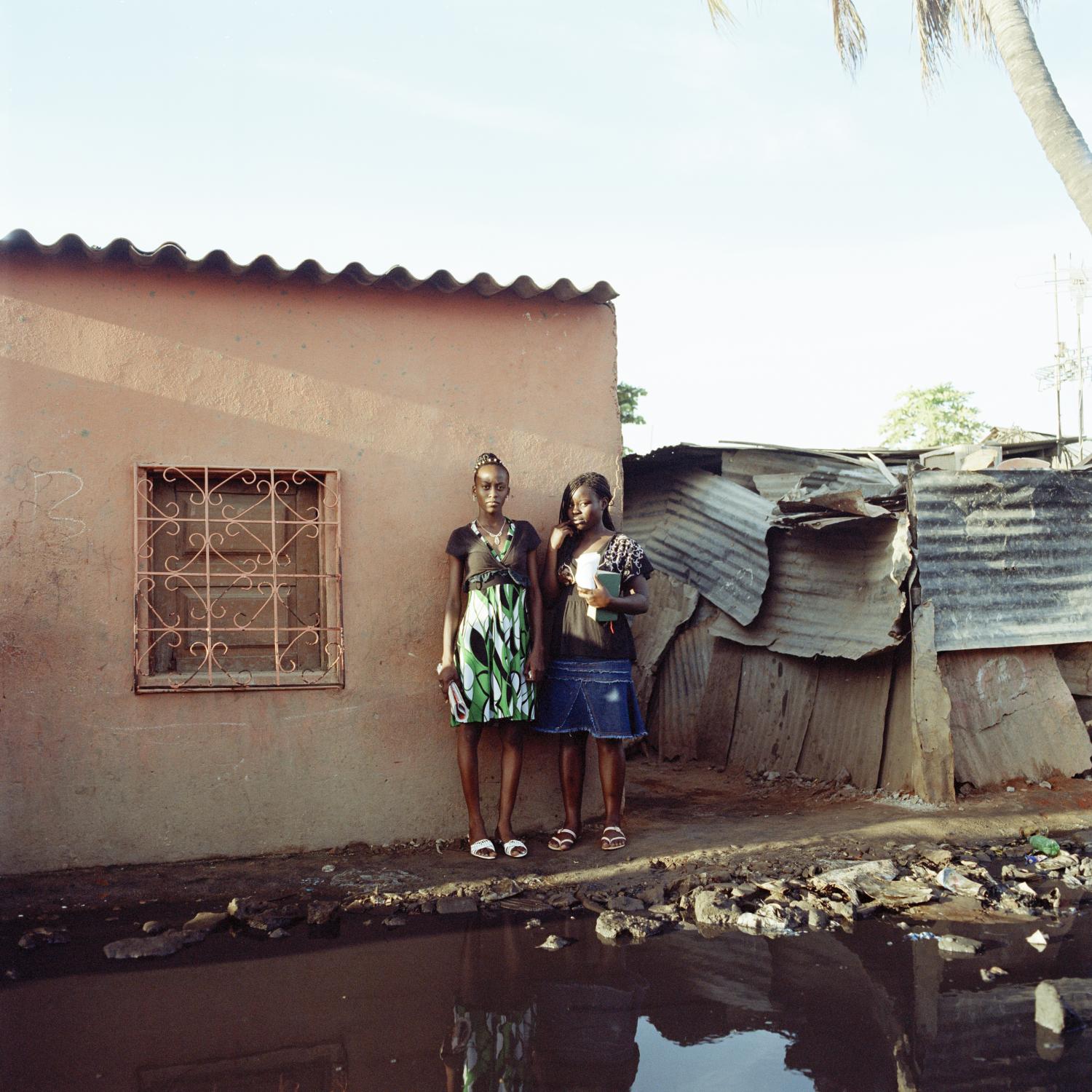 Angola - Girls leave their home in a street flooded with raw...