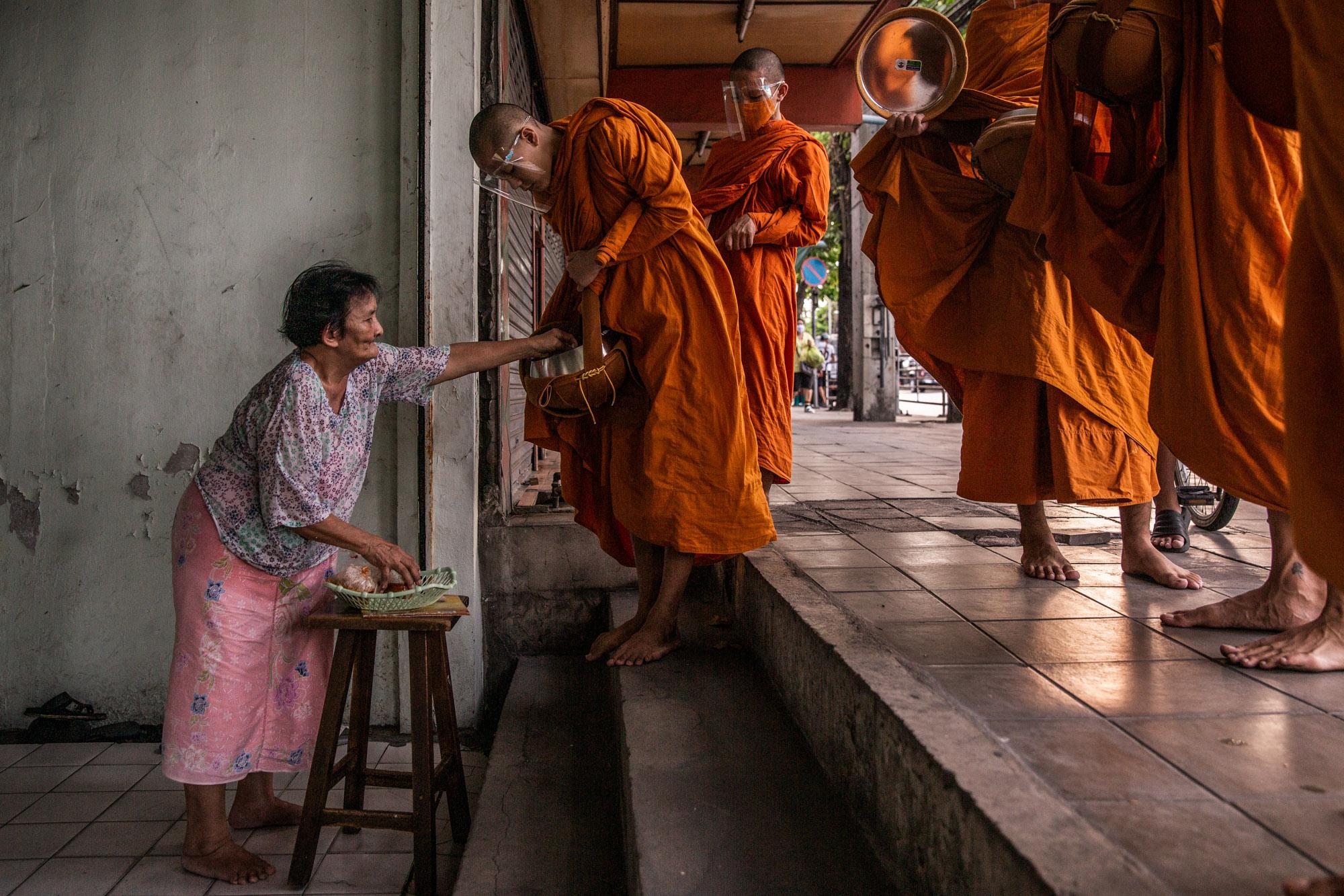 Covid-19: Thailand - Novice Buddhist monks gather alms wearing face shields in...