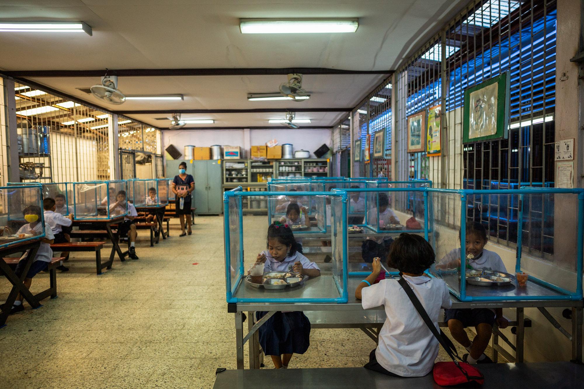 Covid-19: Thailand - Children eat lunch behind social distancing screens at...