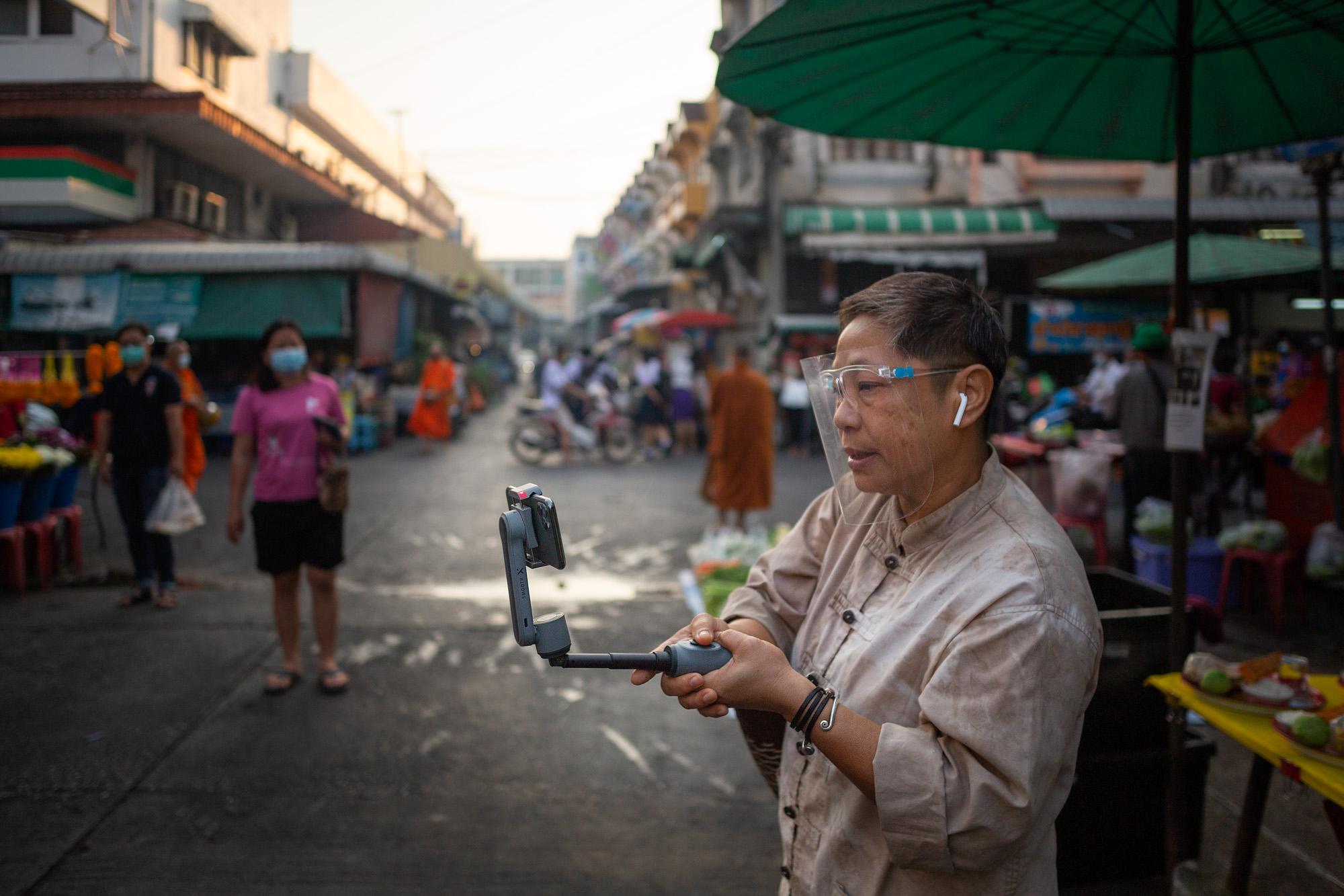 Hnoi Latthitham, 53, leads a virtual tour of Chai Chimplee Temple Market in Bangkok, Thailand, on Monday, February 1, 2021, in Bangkok, Thailand. She shows participants the hustle and bustle of morning life, and stops to explain rituals of alms giving to Buddhist monks.