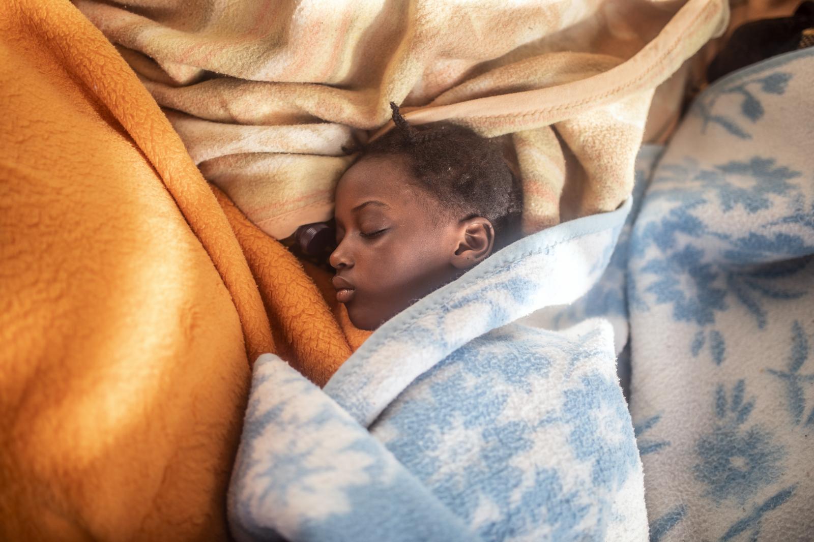 Fleeing the Libyan Clutches - 5 year old Timi sleeps between the blankets at her...