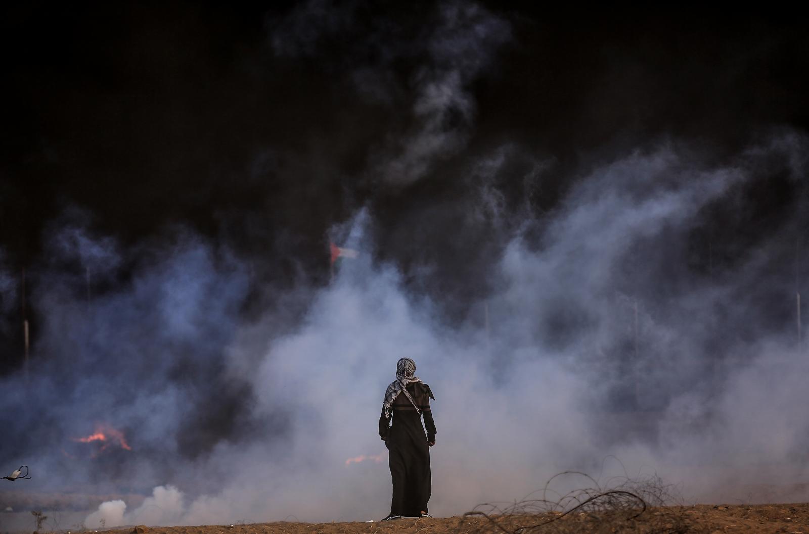 A girl demonstrator stands in front of the tear gas smoke that the Israeli army has thrown during...