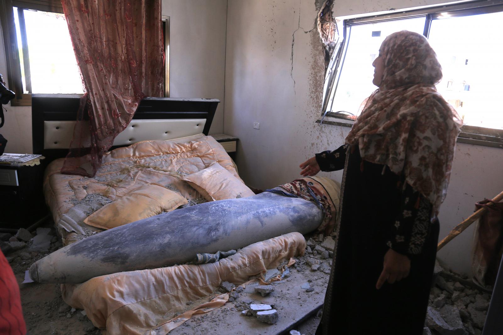 A woman stands in front of an unexploded Israeli missile that fell on her daughter&#39;s bed...