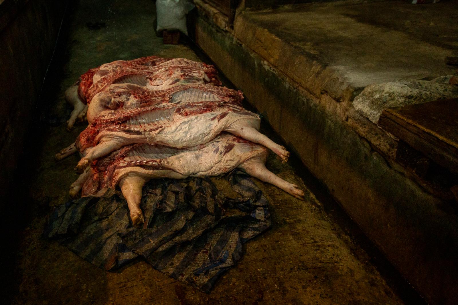 Pig carcasses in front of a butcher shop in the market