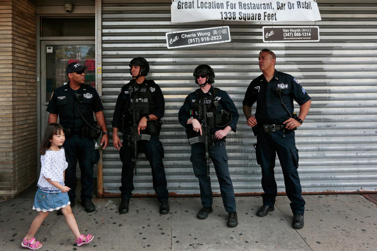 A girl walks by armed NYPD offi... 2017 in Bensonhurst, Brooklyn.