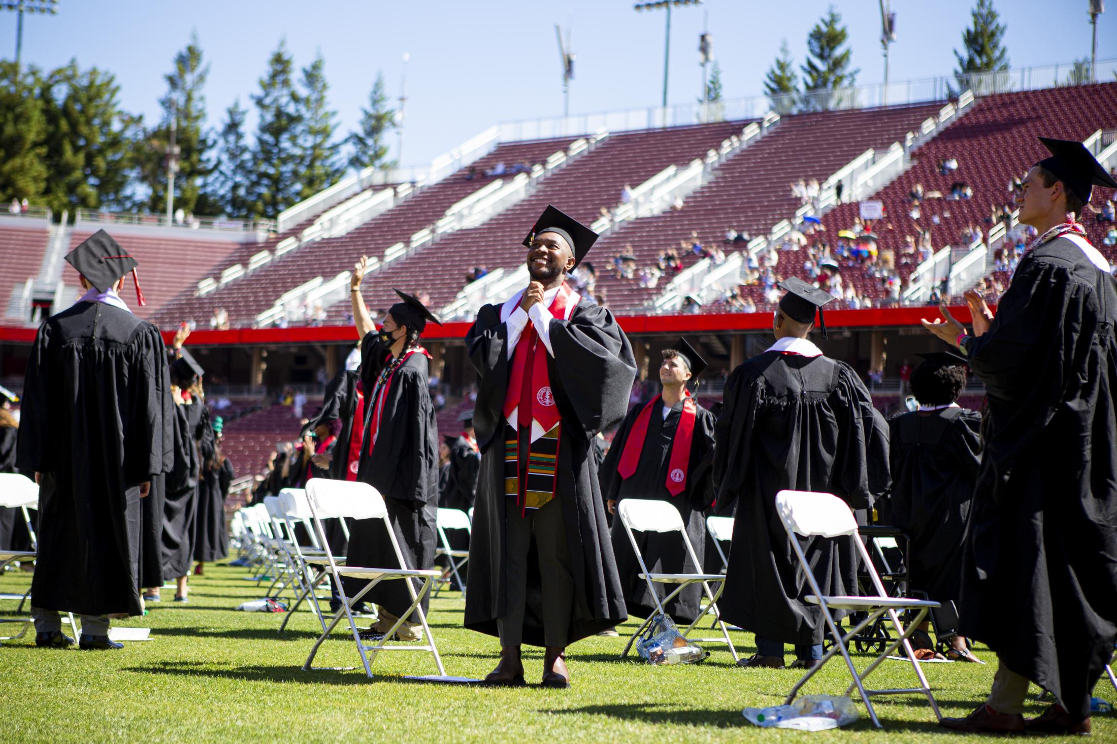 Graduation, at last (Photos for CalMatters) - Ryan Wimsatt joins his hands to thank his parents during the graduation ceremony at Stanford...