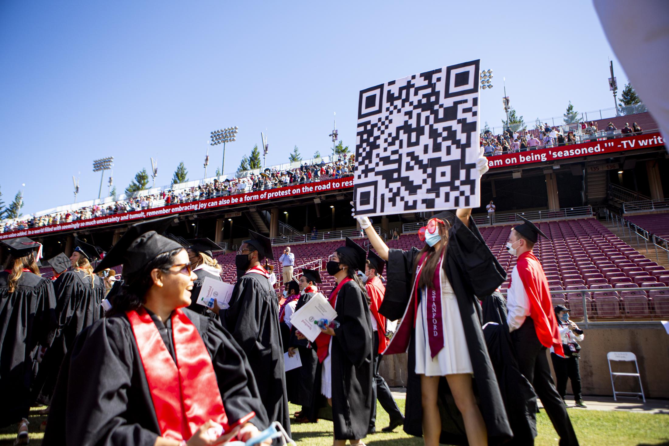 Graduation, at last (Photos for CalMatters) - A student enters the stadium holding up a huge sign with the QR code at Stanford University, in...