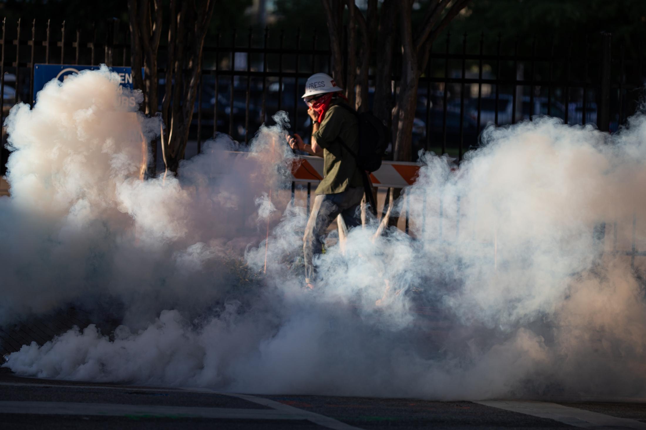 Unrest Dallas - A member of the press runs away from a cloud of tear gas...