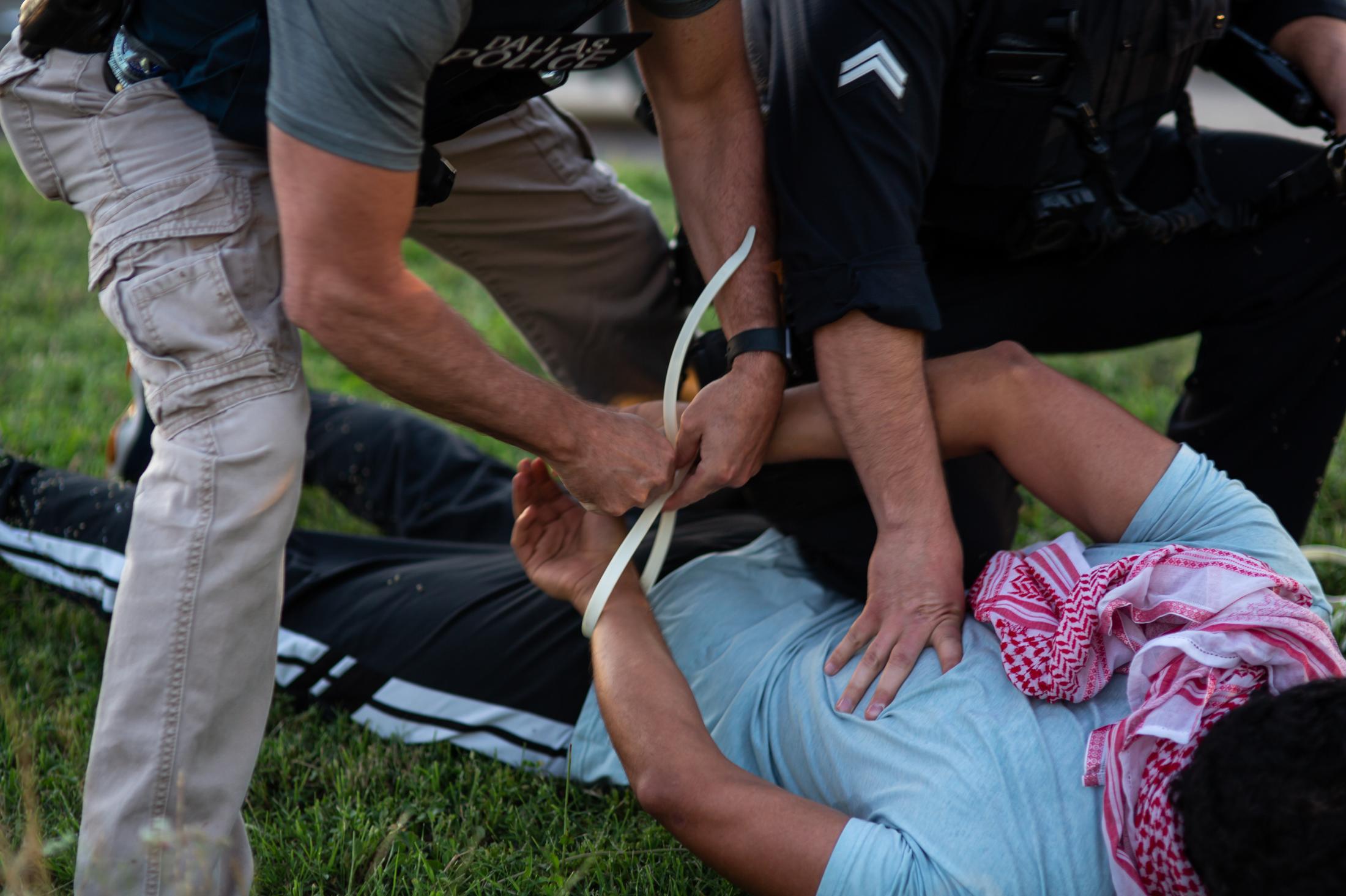 Unrest Dallas - A man is cuffed with other protesters by Dallas Police...
