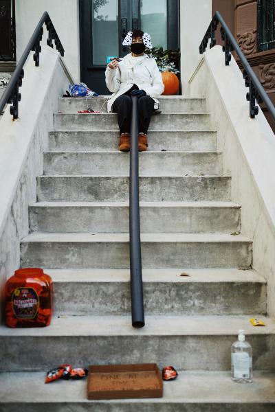 "New York is Back"? - A local on her stoop with a candy chute to distribute candy in a socially distanced manner during...