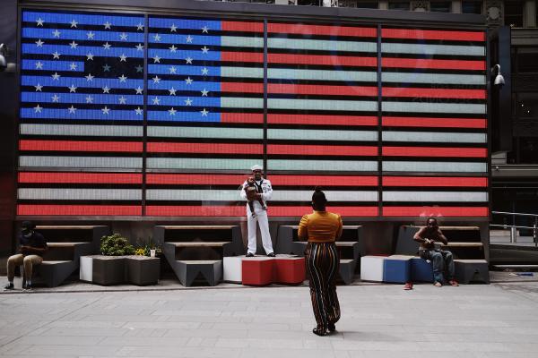 "New York is Back"? - Family taking pictures in front of an LED USA flag in Times Square during Fleet Week. May 2020,...