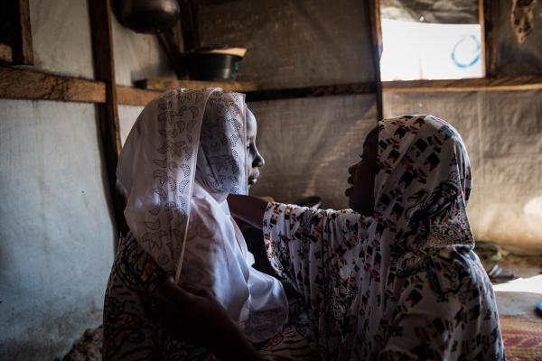 Halima* and her sister share a moment as she prepares to go out.