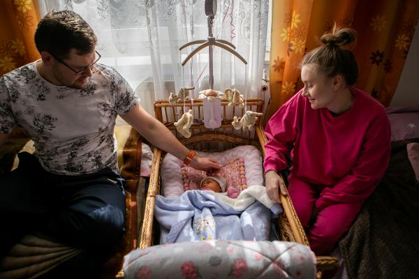 Image from OVER THE BORDER -  Olena and Andreii Tsebenko hold Vira, who was born last...