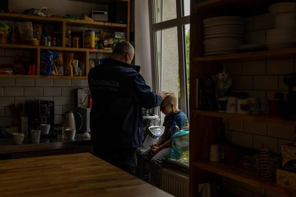 Image from "MY LIFE IS IN DANGER" - for NYTimes - Father Kancelarczyk talks with a young boy named Denis in...