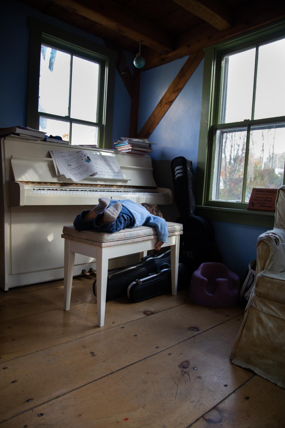 Isaak lays on the piano chair on a winter morning Bremen, Maine, 2014.