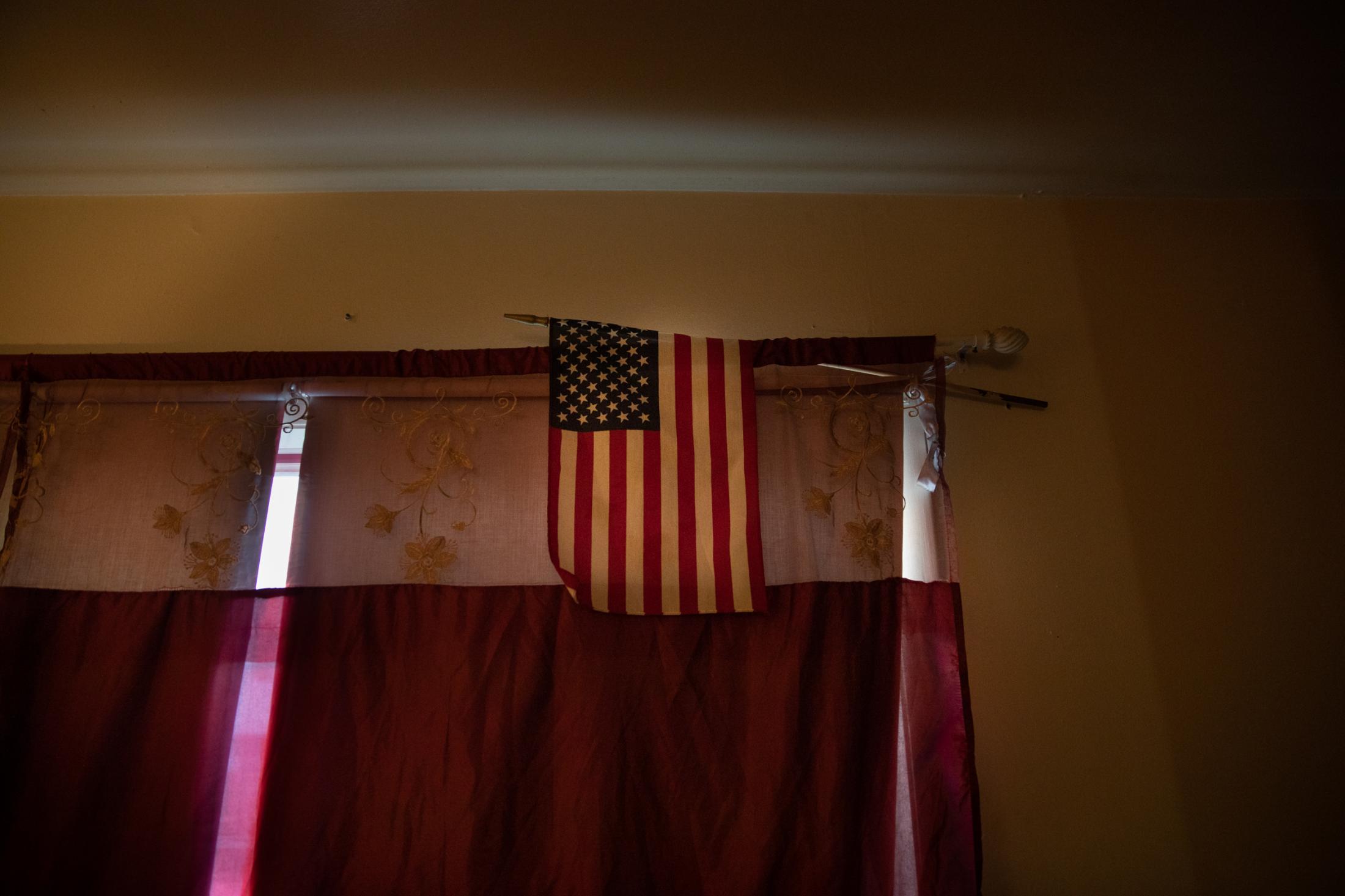 An American flag stands alone by the window in a Sudanese house in Portland, Maine, 2021.