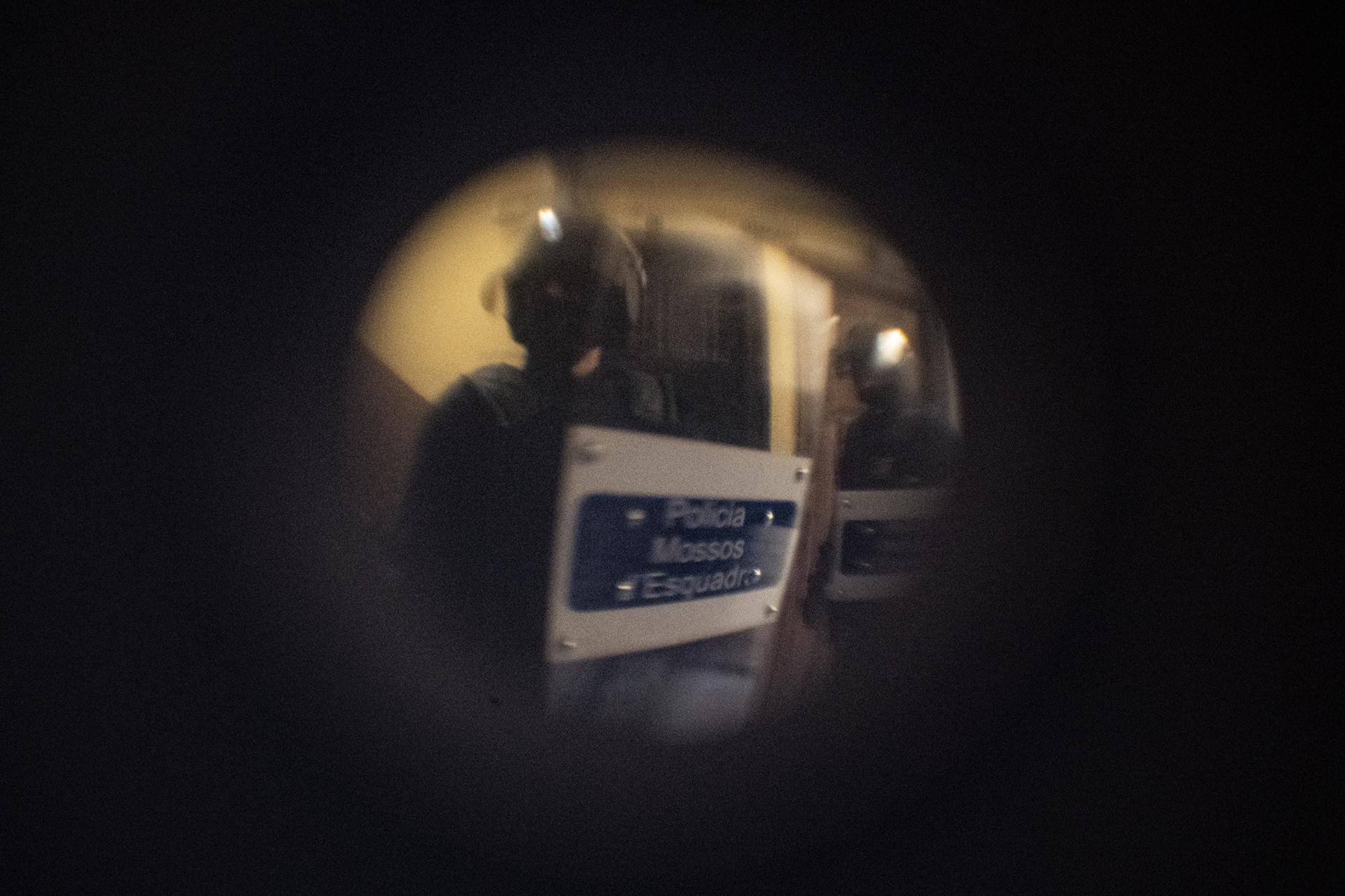 Barcelona Housing Crisis (ongoing) -  Police officers, seen through the door’s spyhole,...