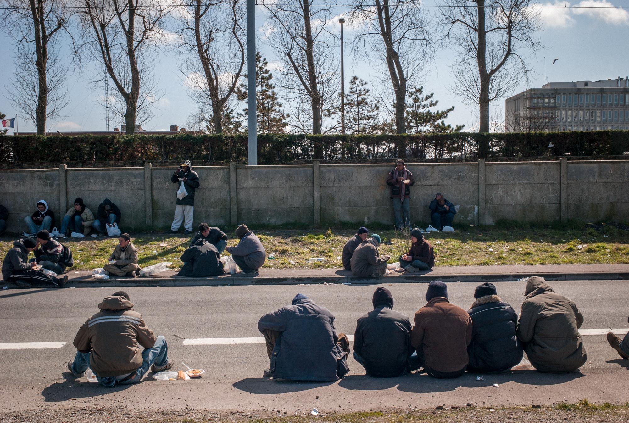 Migrants in Calais, France (2008) - Immigrants eating daily midday meal provided by the...