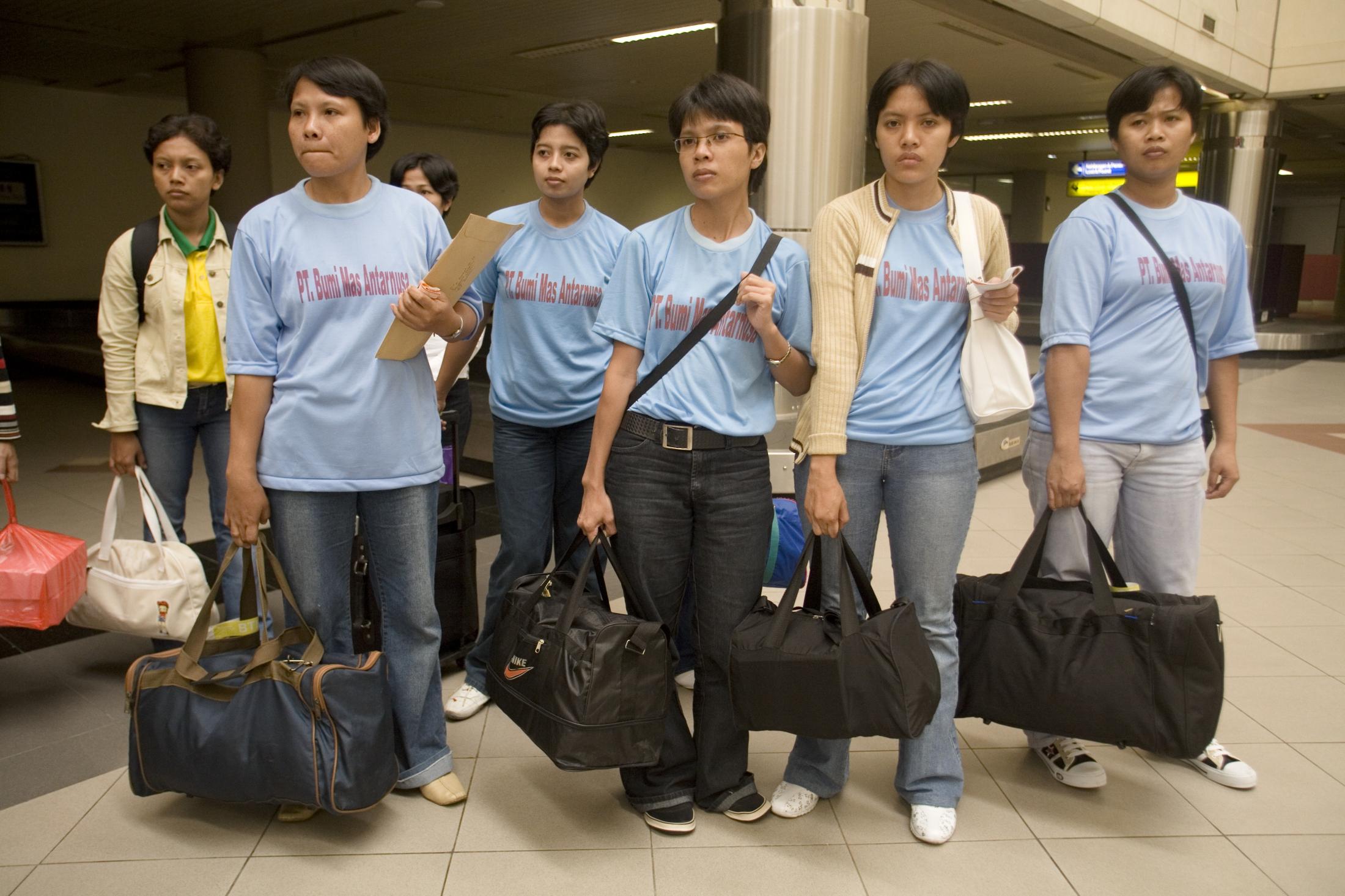 Young women wait for their labor agent in a special section of Hang Nadim airport for domestic...