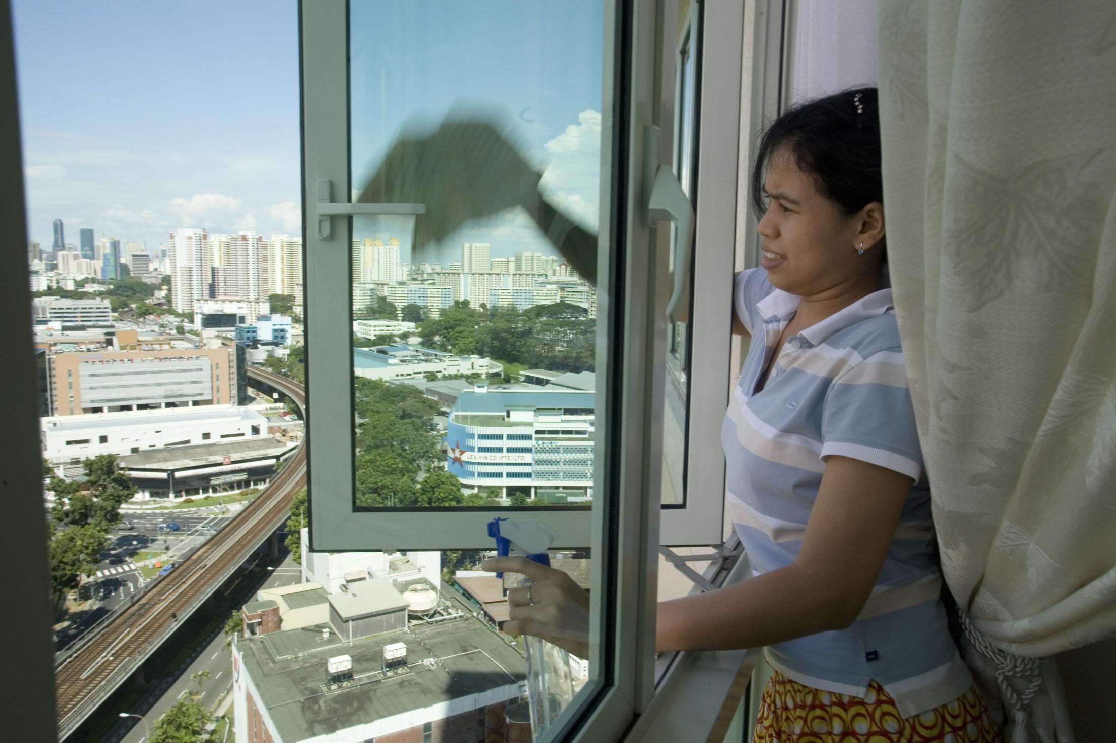 Mina, 27, washes the windows at a high-rise condominium. Approximately 150 domestic workers have...