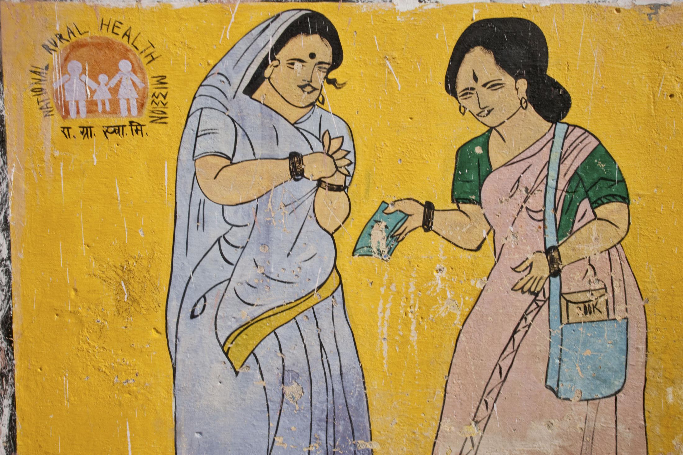 Painted wall announcing government program to pay women for their hospital deliveries. Barabanki,...