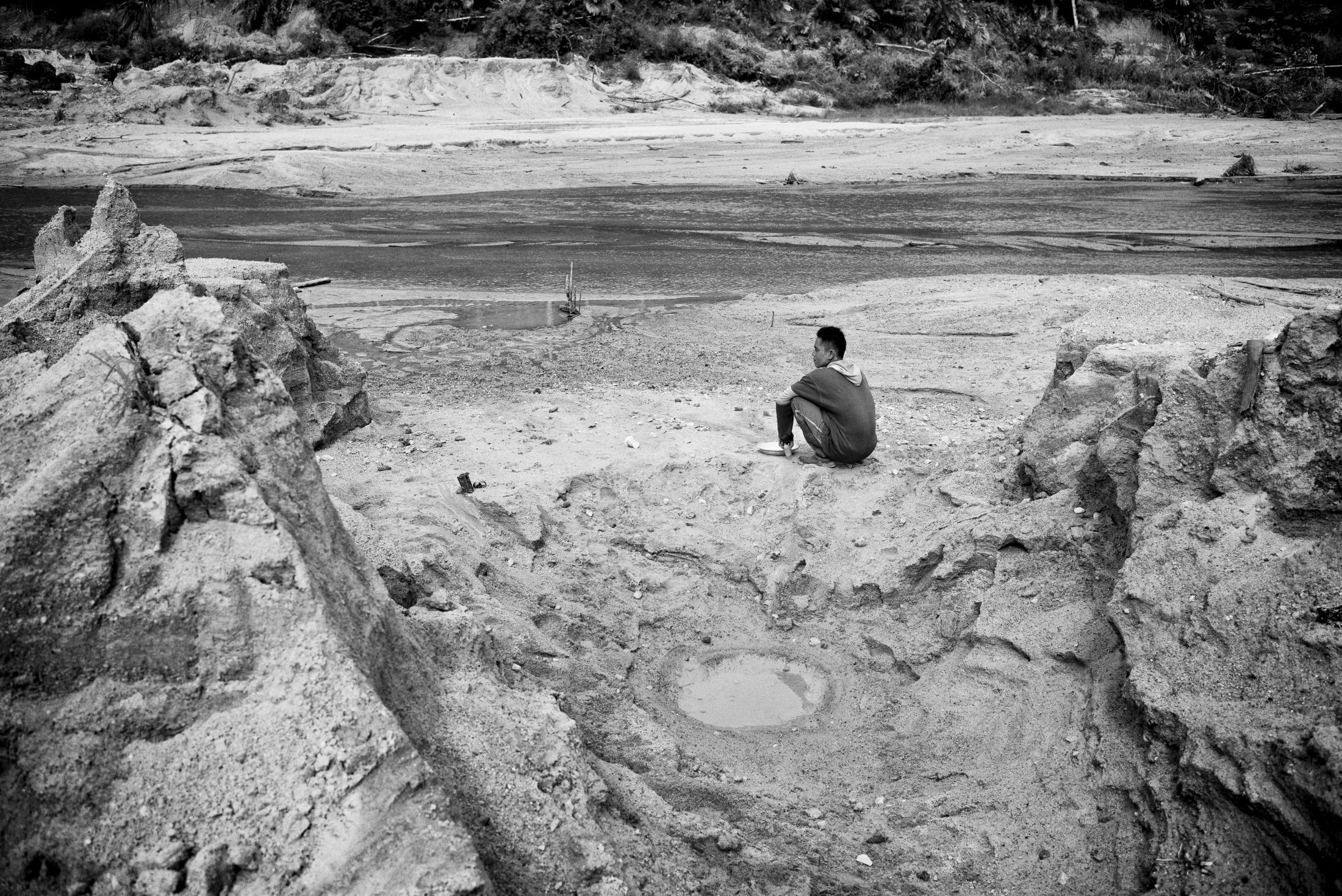 The Cursed Island of Tin - Riki, an illegal tin miner, sits and rests at an open pit...