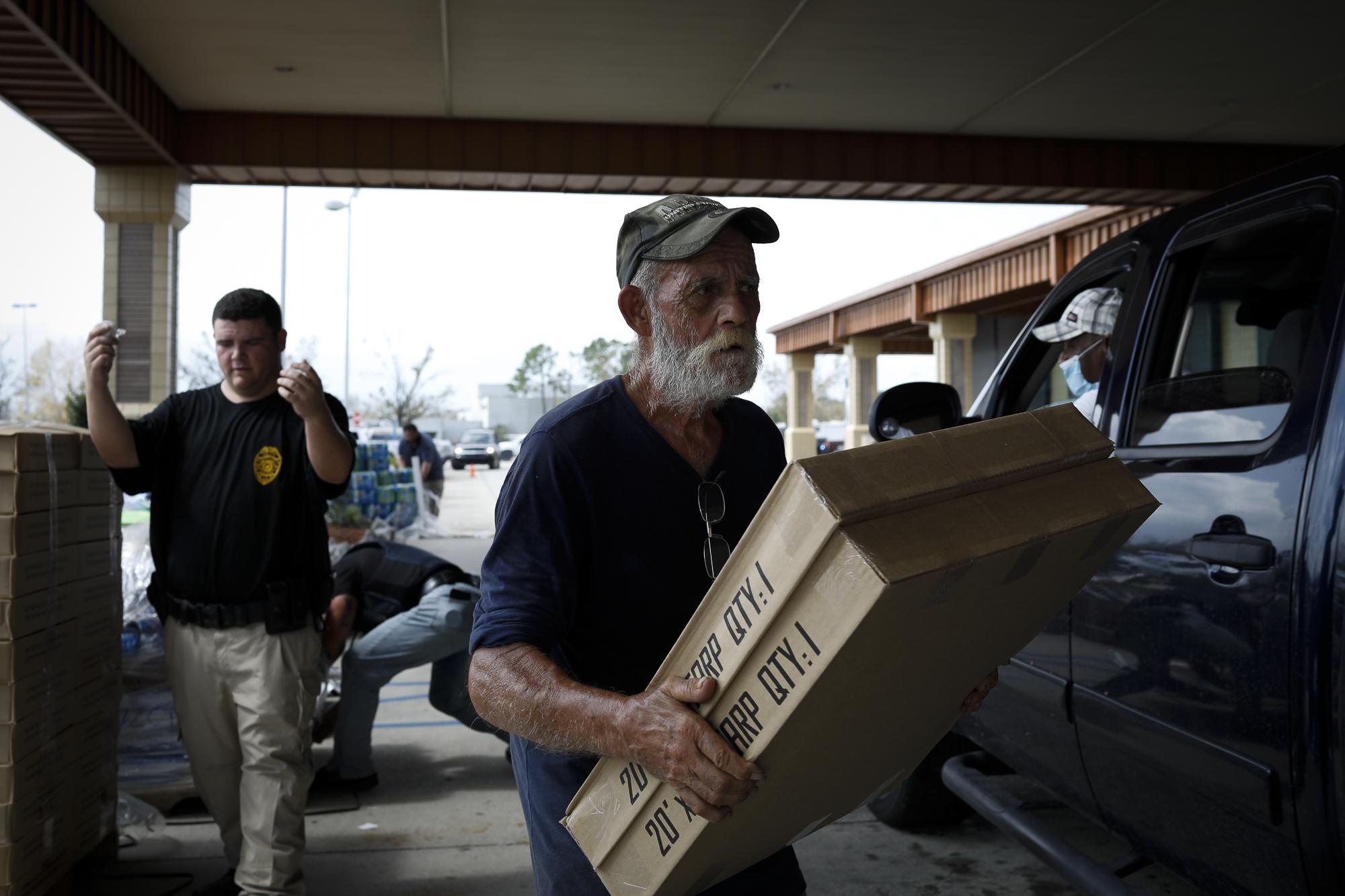 Hurricane Ida in Louisiana - A volunteer carries boxes of tarp in the back of a car as...