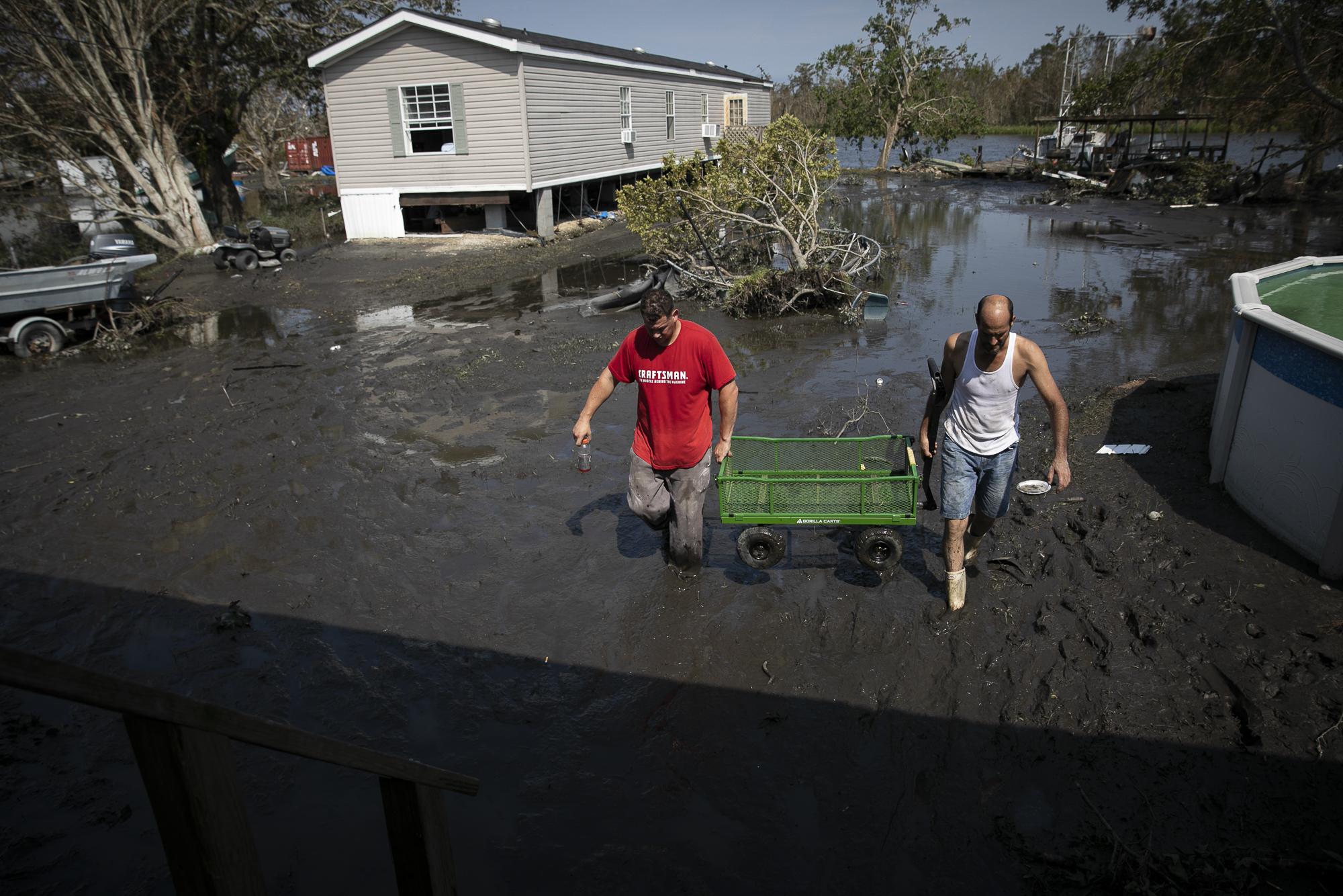 Hurricane Ida in Louisiana - Nathan and Marcus Encalade carry a cart as they clean...