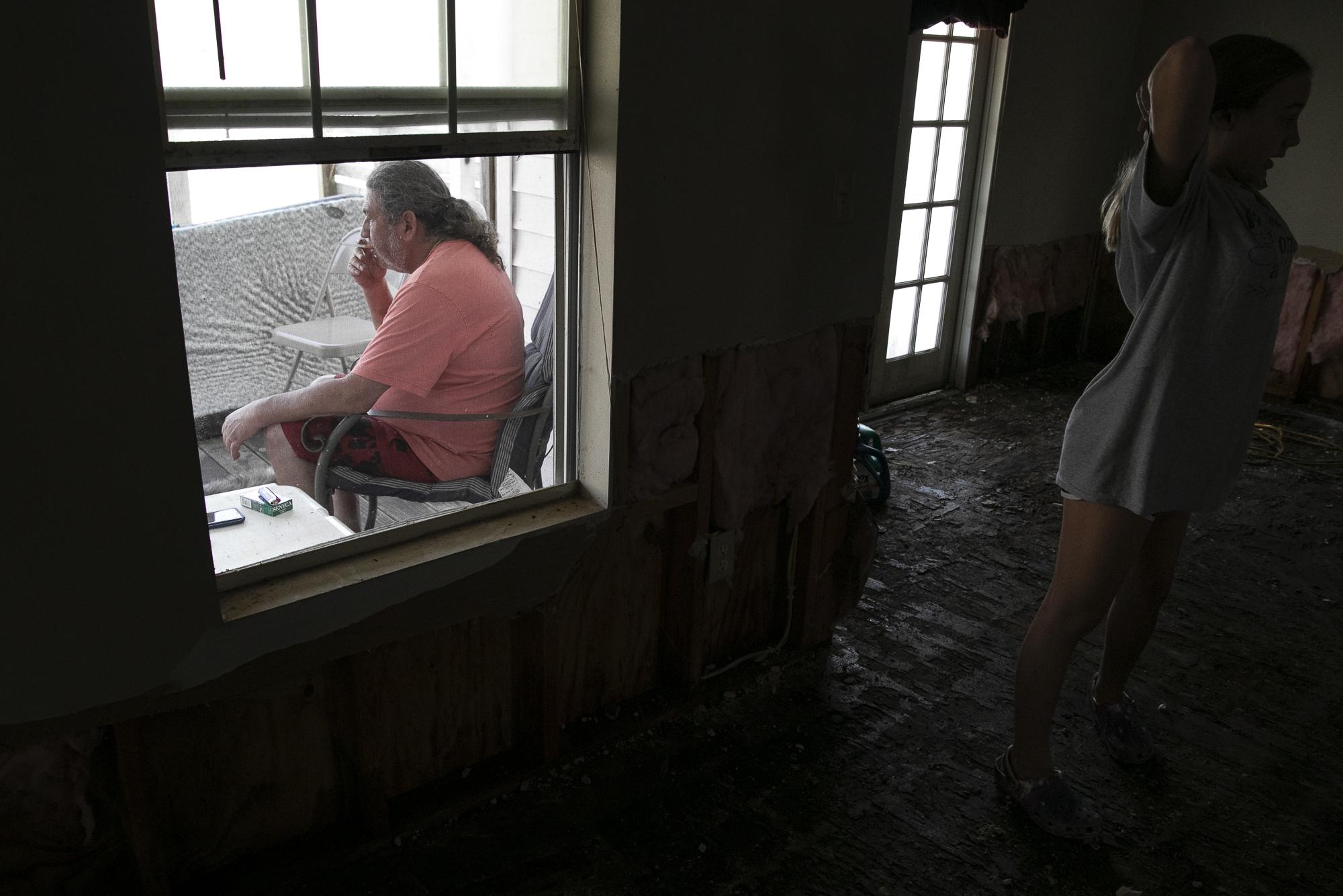 Hurricane Ida in Louisiana - Nathan Encalade smokes a cigarette as his family clean...