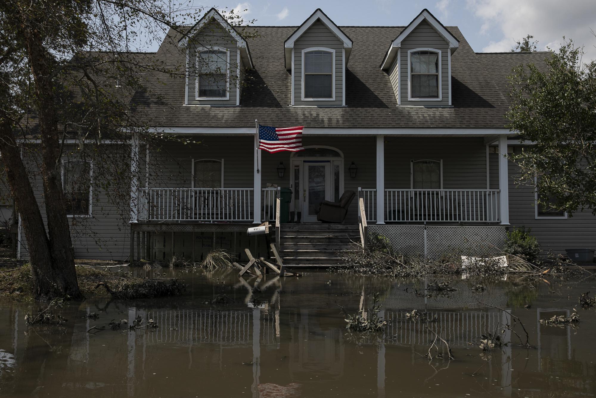 Hurricane Ida in Louisiana - An American flag flies in front of a house in a flooded...