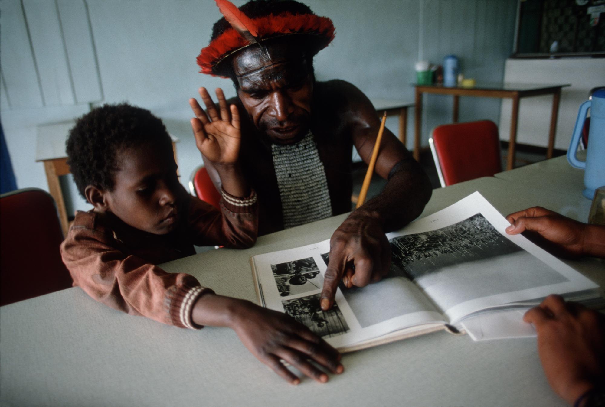Pua shows his daughter the book &quot;Gardens of War&quot; with photographs by Robert...
