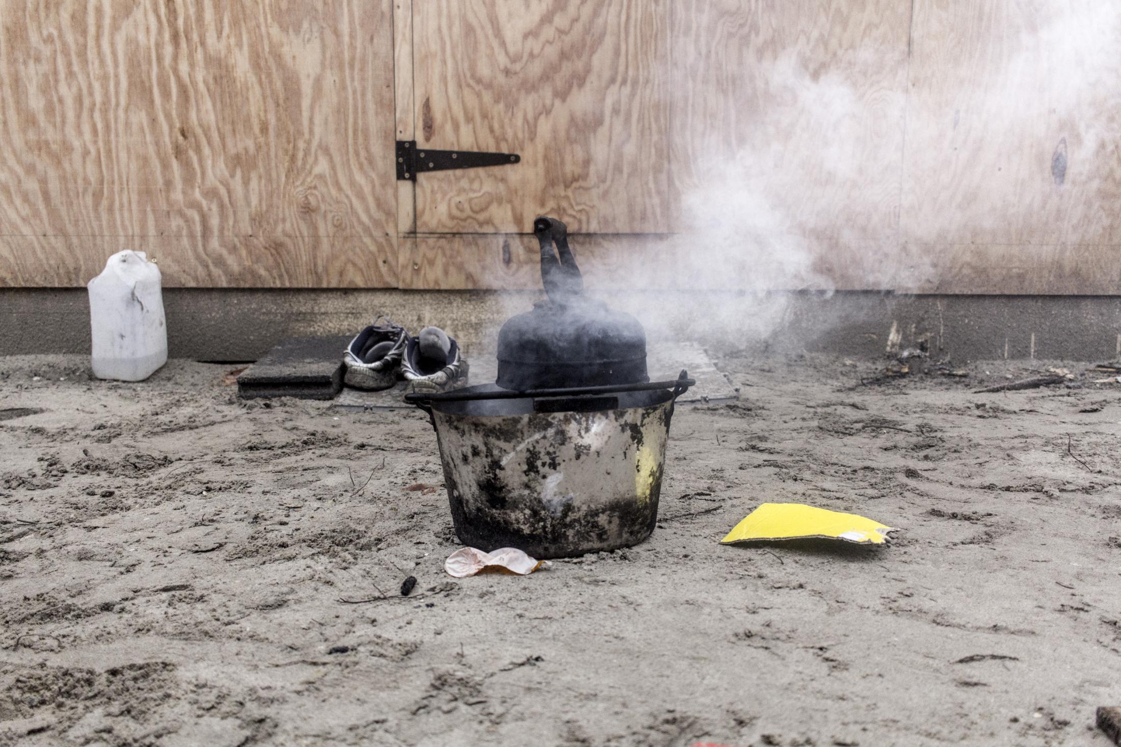 Latent urbanities - Afghan people cook outside their shelter in the New Jungle, Calais&#39;refugees camp. New...
