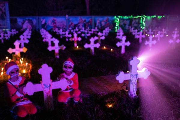 Children are dressed as Shanta Claus and roam around the decorated cemetery on Christmas eve in Savar, Dhaka, Bangladesh.