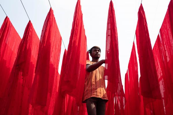 At a dye factory in Narayanganj, Bangladesh, a worker dries fabrics after applying color.