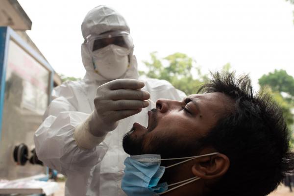 A man reacts as a health worker wearing protective gear takes a swab from him to test for coronavirus disease (COVID-19) at a hospital in Dhaka, Bangladesh.