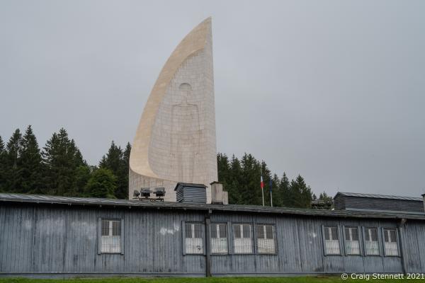 Natzweiler-Struthof Concentration Camp, Natzweiler, Bas-Rhin, France, 11th September 2021. The Monument to the Departed stands behind a section of the prisoners accommodation at Natzweiler-Struthof a Nazi concentration camp located in the Vosges Mountains in the Gau Baden-Alsace, on territory annexed by Germany in 1940. The camp operated from 21st May 1941 through to September 1944 and was the only concentration camp established by the Nazis on pre-war French soil. Roughly 52,000 prisoners were held there. They were mainly from the French Resistance. It operated as a labor camp, transit camp, and as the war went on, a place of execution (estimated 22,000 deaths). The inmates came from 32 different nations. An annual remembrance ceremony is held for all who were interned there and all who died. 2021, a special ceremony was held for Sergeant Frederick Habgood, who was a crew member of a Lancaster Bomber shot down over France on July 29, 1944. Sergeant Habgood was captured by the Gestapo, taken to the concentration camp and immediately hanged. His body was cremated at the site and his ashes flung into the &#39;Ash Pit&#39;. However, his silver bracelet, engraved with his name, miraculously survived. This bracelet was handed back to the surviving members of the Habgood family by Genevi&egrave;ve Darrieussecq, Secretary of State to the Minister of the Armed Forces for France.