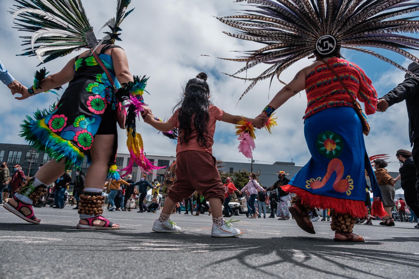 Traditional dancers and visitors perform a friendship dance to kickoff the beginning of Carnaval celebrations in San Francisco on Saturday, May 29, 2021. For the second year, CANA-Carnaval San Francisco will hold a community resource fair in place of its traditional parade and festival. The event will celebrate the resilience of those who have been disproportionately affected by the pandemic and provide numerous health and economic equity resources.